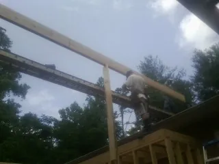 Carpenter setting a ridge beam over a new addition frame — Ice Dam Removal by Roofing Brothers in Clarkston