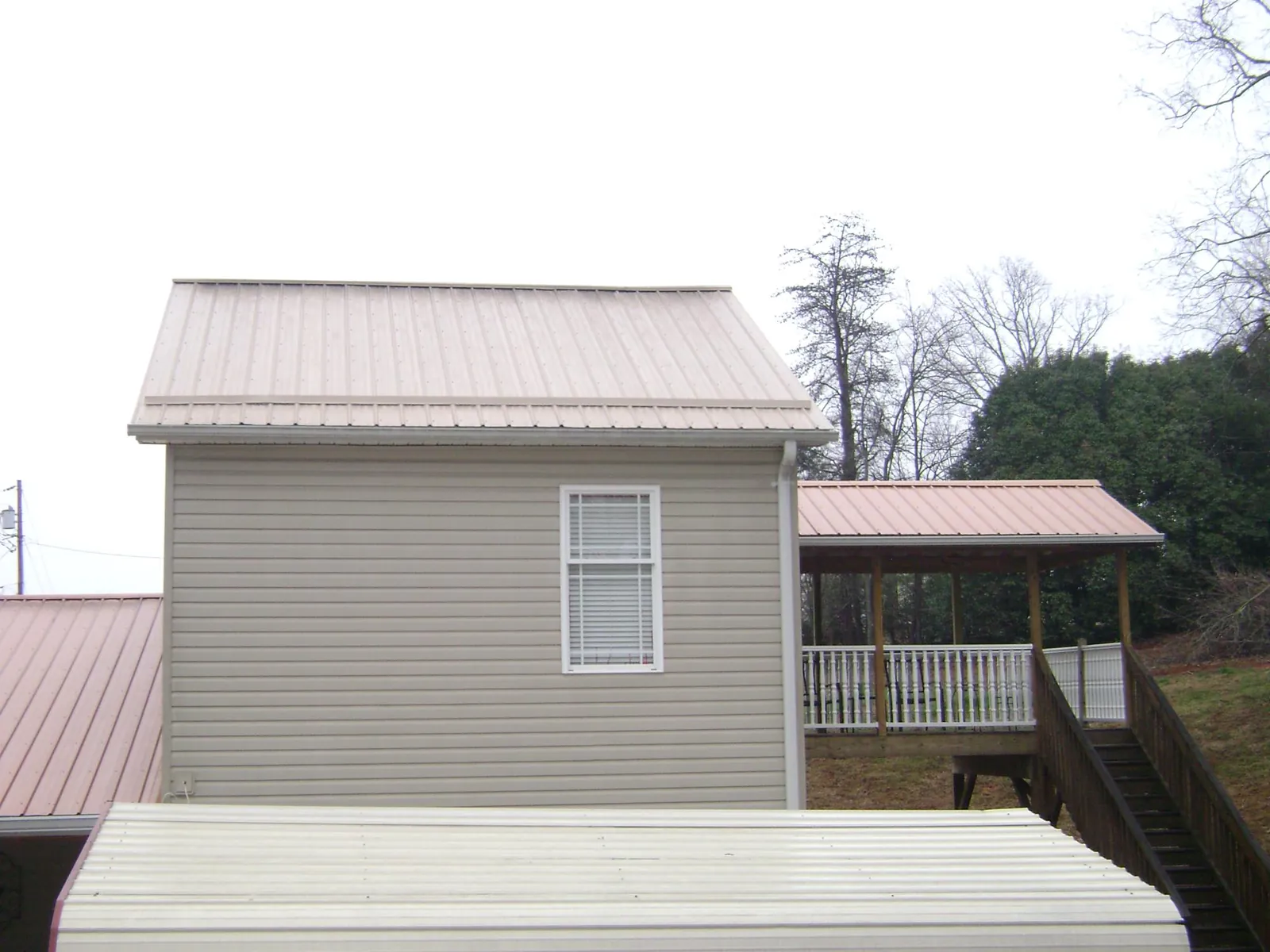 Tan metal roofs on a two story addition and attached porch, from a Roof Replacement job in Clarkston